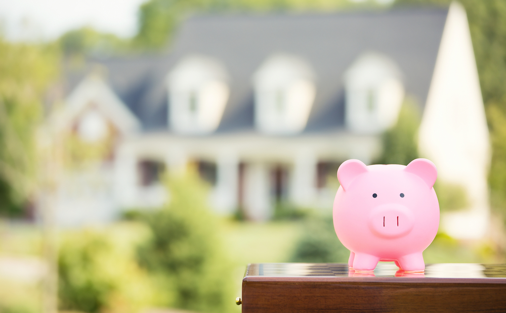 Real estate sale, home savings, loans market concept. Housing industry mortgage plan and residential tax saving strategy. Piggy bank isolated outside home on background. Focus on piggybank. Homeowner Real estate sale, home savings, loans market concept. Housing industry mortgage plan and residential tax saving strategy. Piggy bank isolated outside home on background. Focus on piggybank. Homeowner