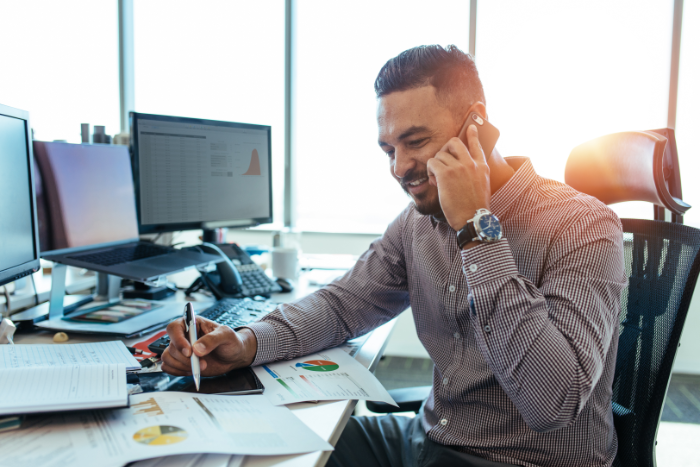 A man at work discussing the benefits of AML software for accountants over the phone