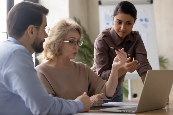 An older woman showing her compliance team how to use AML software An older woman showing her compliance team how to use AML software